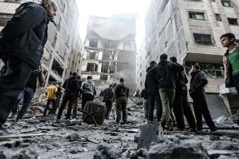 Des Palestiniens se rassemblent sur le site d'un immeuble en ruines après des frappes aériennes israéliennes dans la bande de Gaza