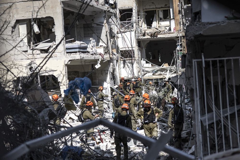 Des secouristes israéliens recherchent des victimes parmi les décombres d'un bâtiment endommagé à la suite d'un tir de missile iranien à Bat Yam, le 15 juin 2025.